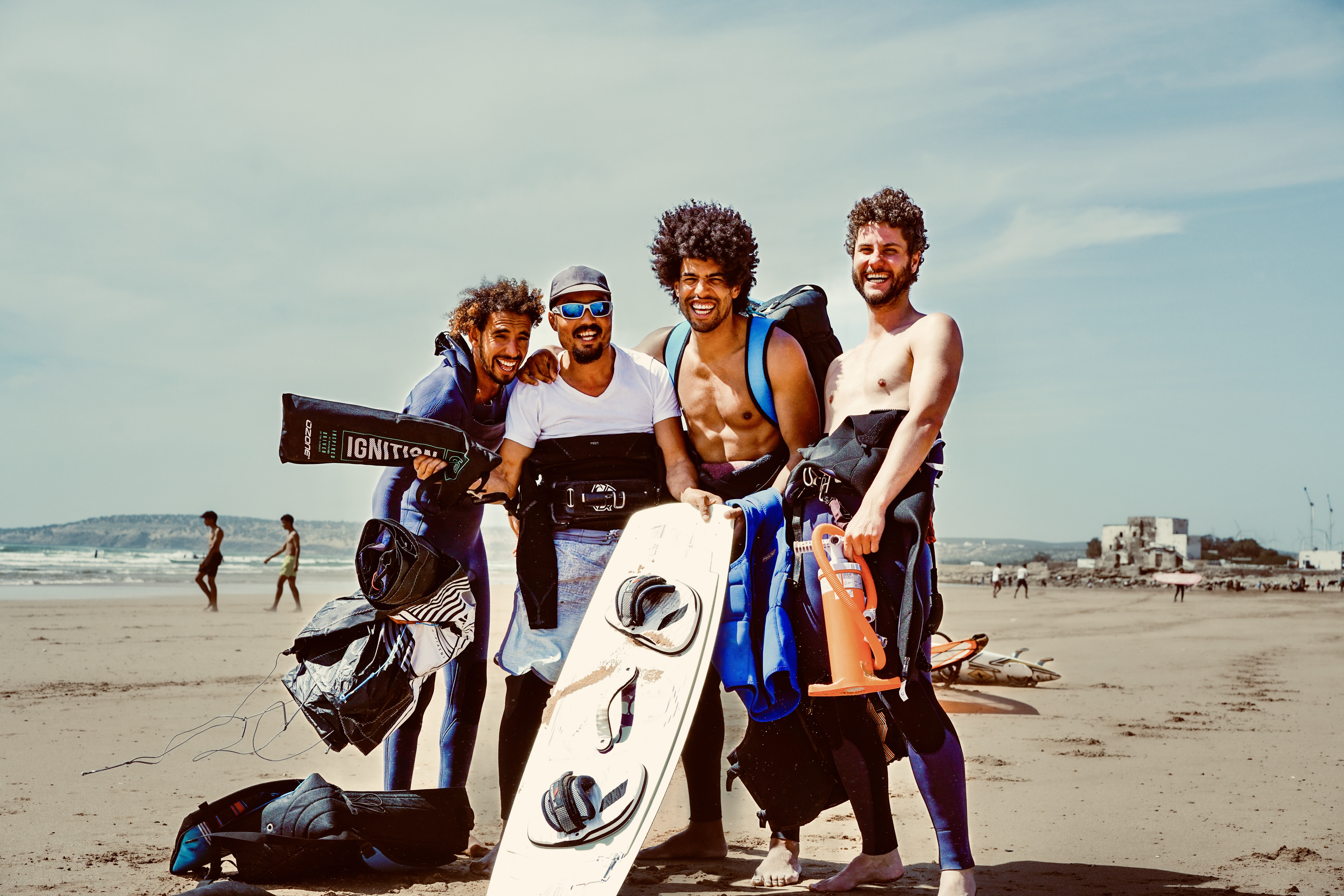 Friends laughing together on Essaouira beach with kiteboards