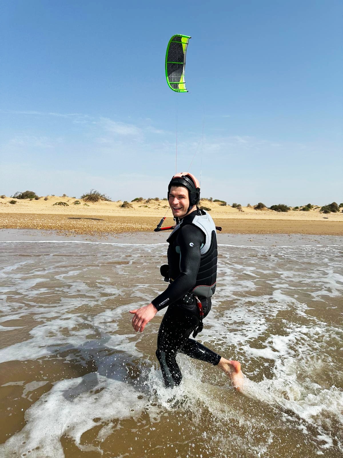 Student running through the water with kite overhead