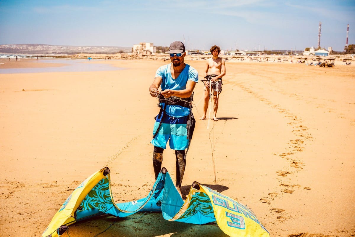 Amine and student setting up a kite together on the beach