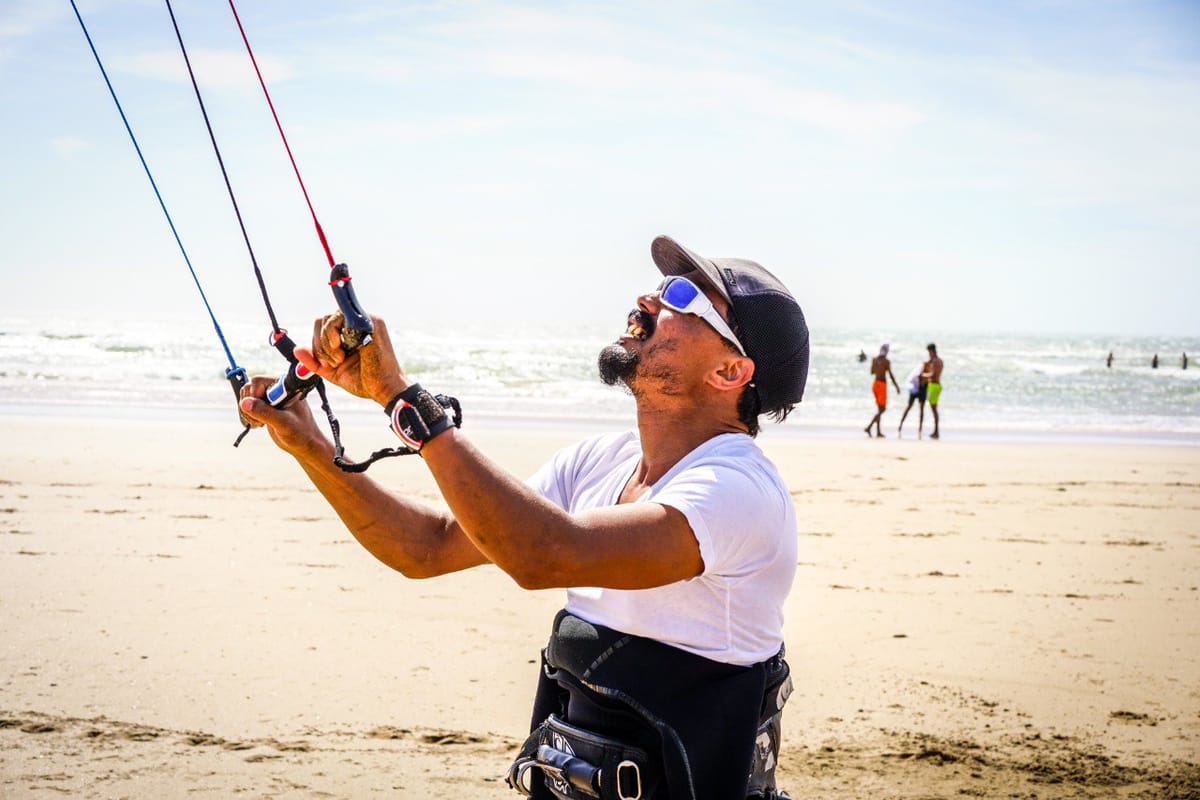 Amine smiling while controlling kite lines on the beach